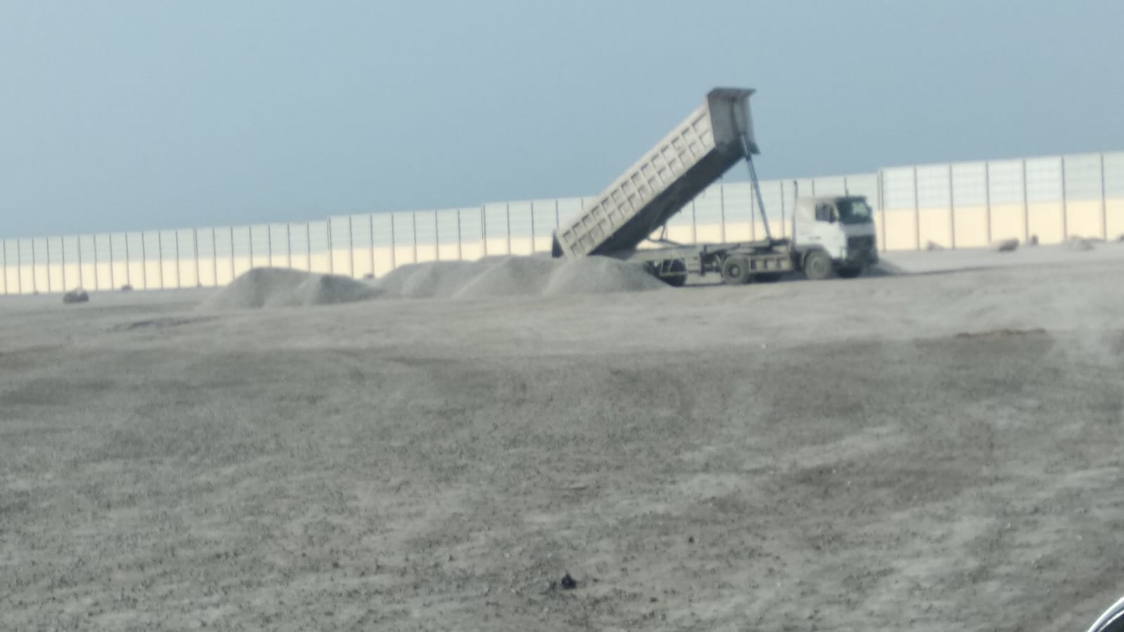 Cargo conveyor and trucks at a bulk cargo operation