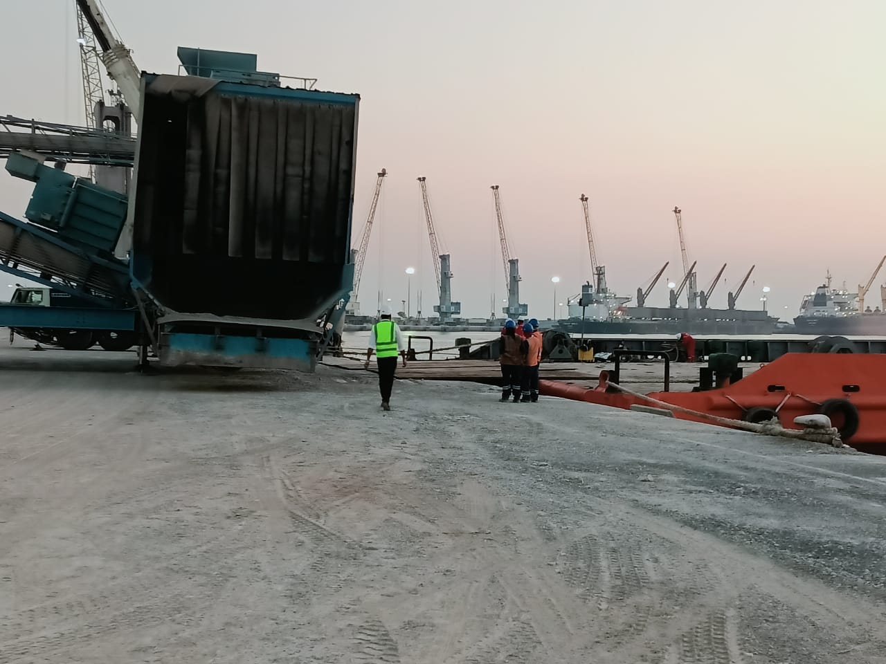 Personnel beside cargo-handling equipment at the quay