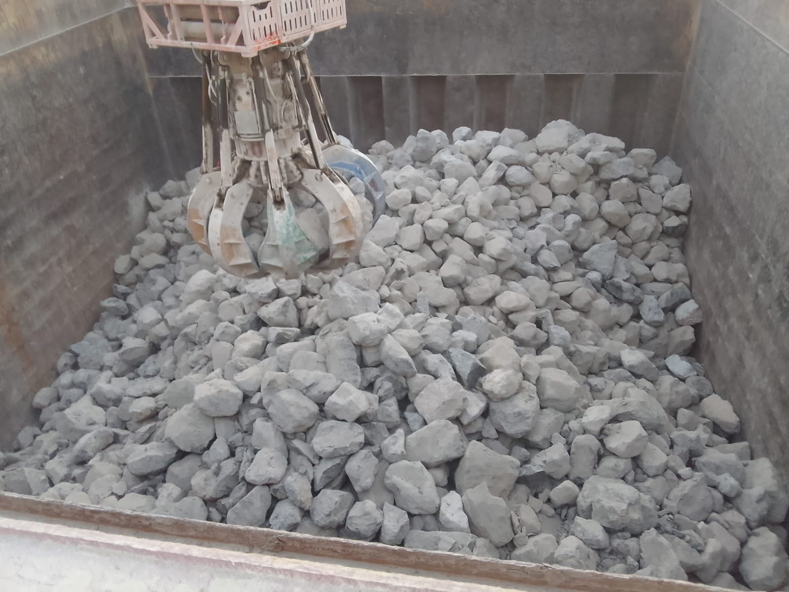 Open grab equipment positioned over rock cargo in the vessel hold