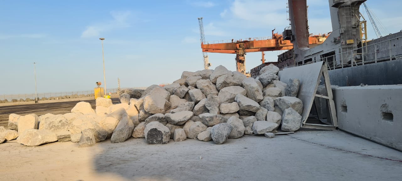 Large rock cargo on the quay alongside a cargo vessel