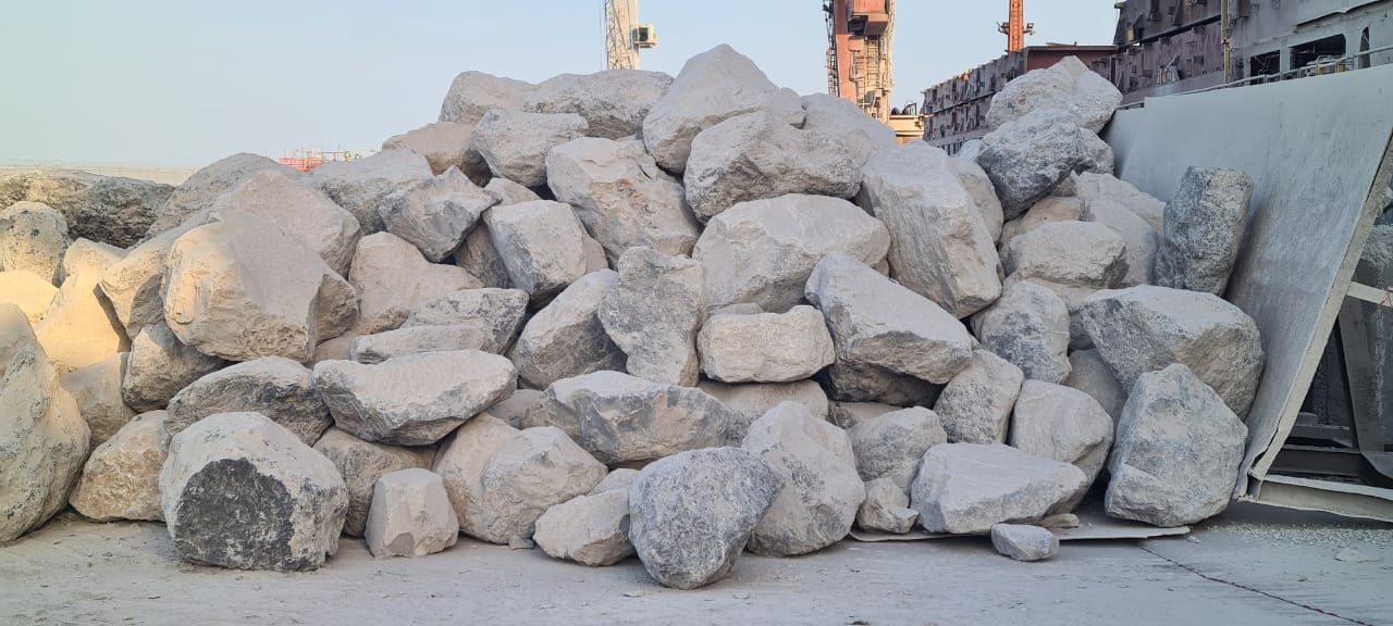 Large rock pieces positioned at the quayside beside a vessel