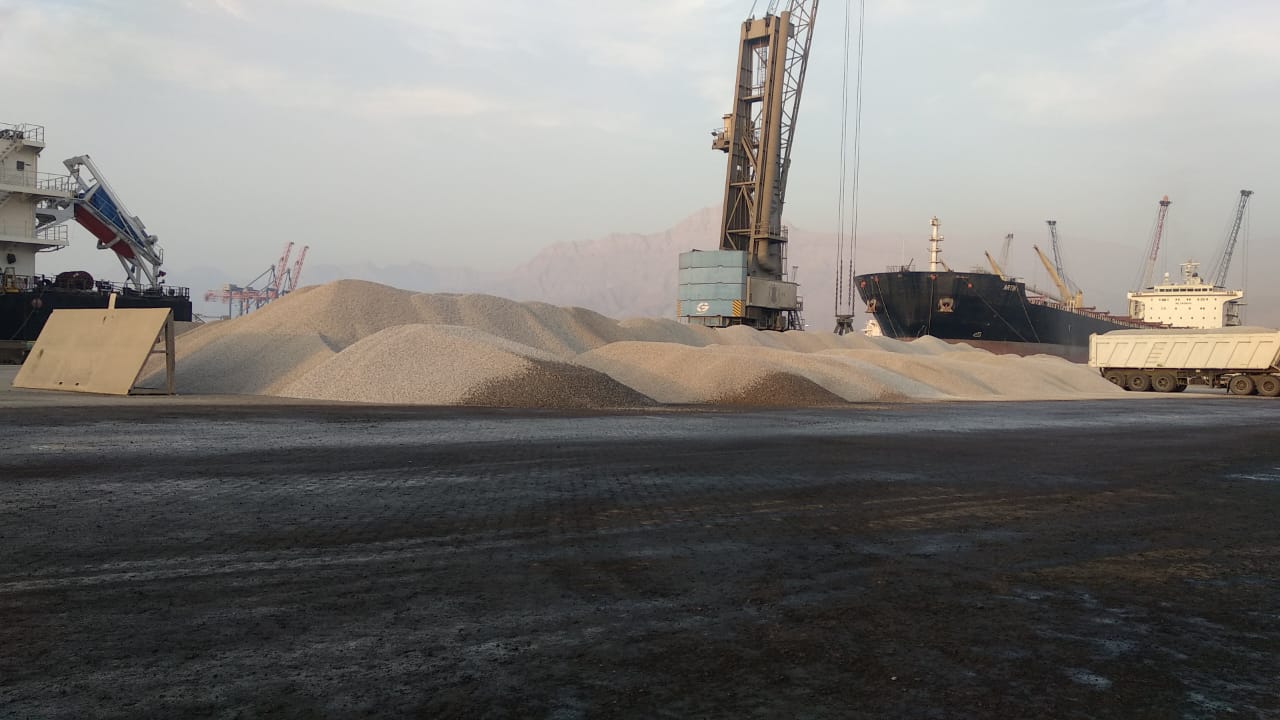 Bulk cargo stockpiles and cargo equipment alongside a vessel