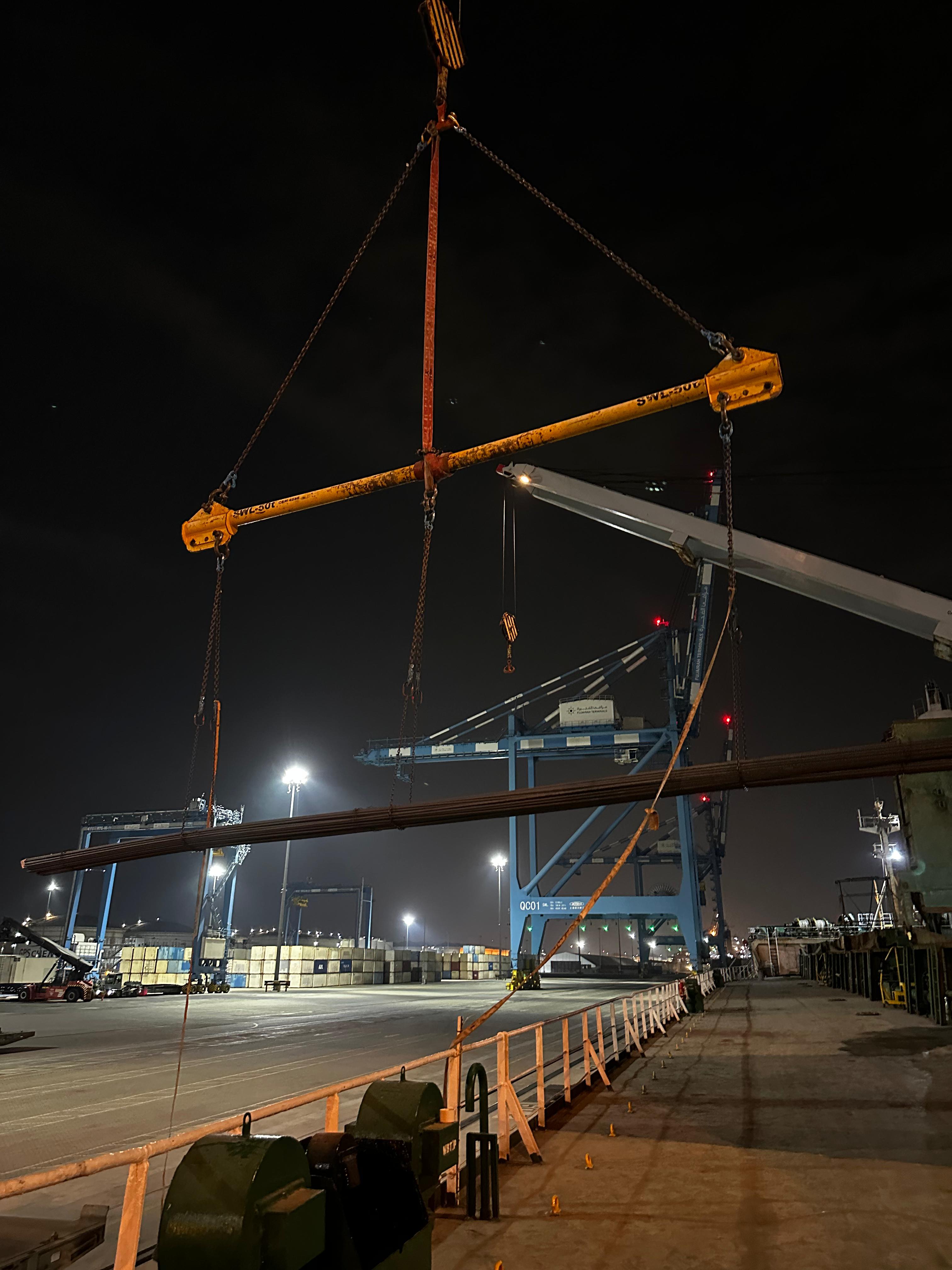 Rigging and spreader beam supporting long cargo during a night-time operation